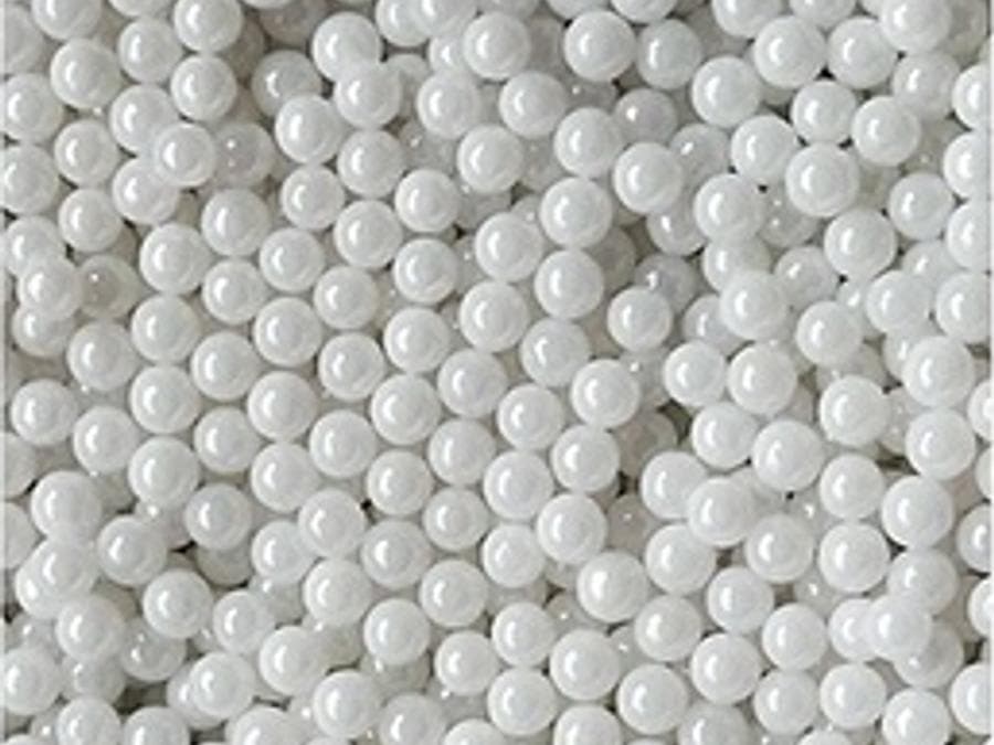 White zirconia grinding beads photographed in mass against a grey background