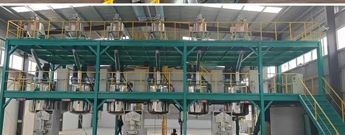 Wide view of the partner workshop: rows of emulsifying and dispersing kettles on a steel platform with bead mills on the floor below